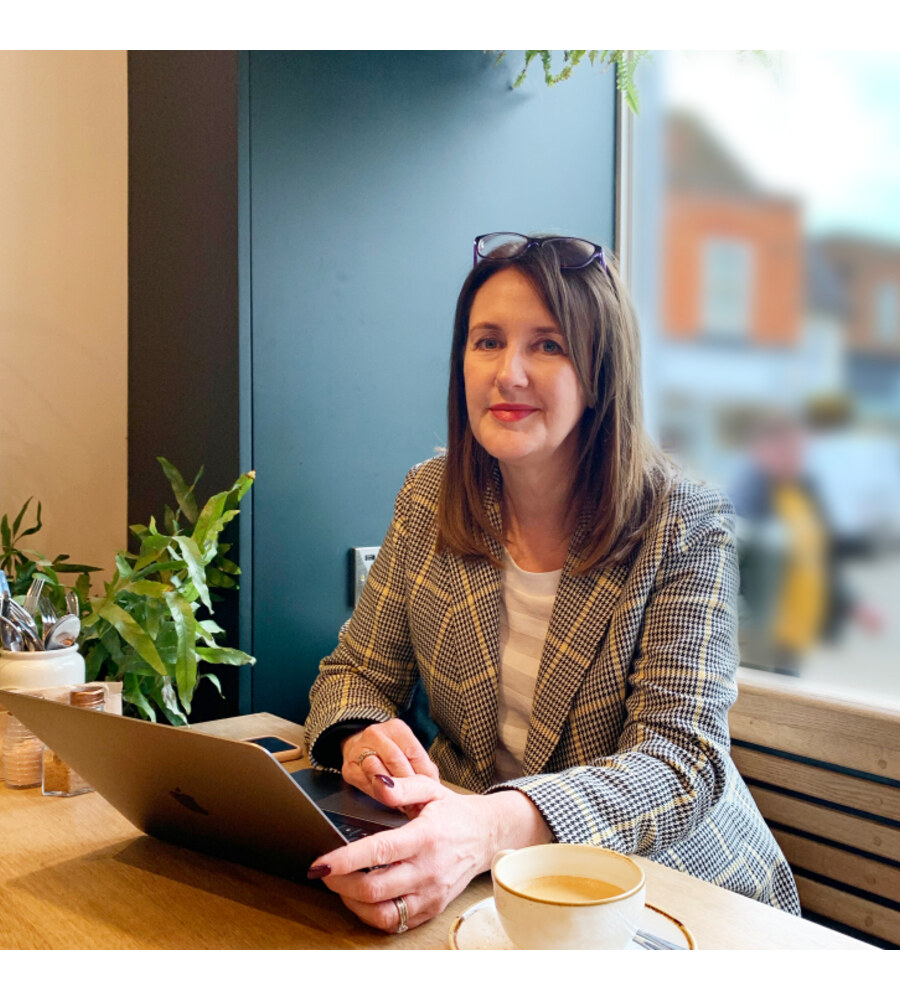 Helen Fraser, leadership coach, working at a cafe table with her laptop