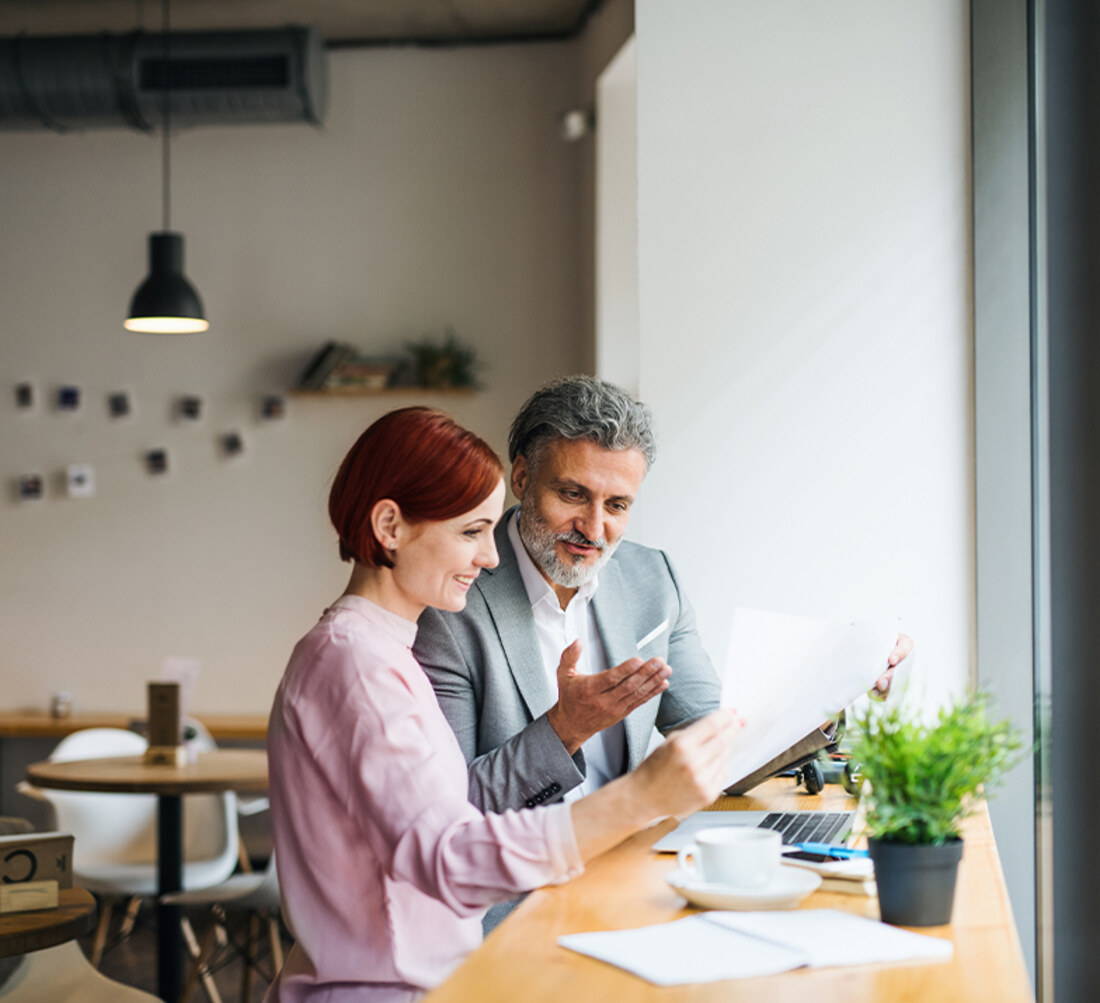 Two colleagues reviewing notes together at a cafe table during a working session
